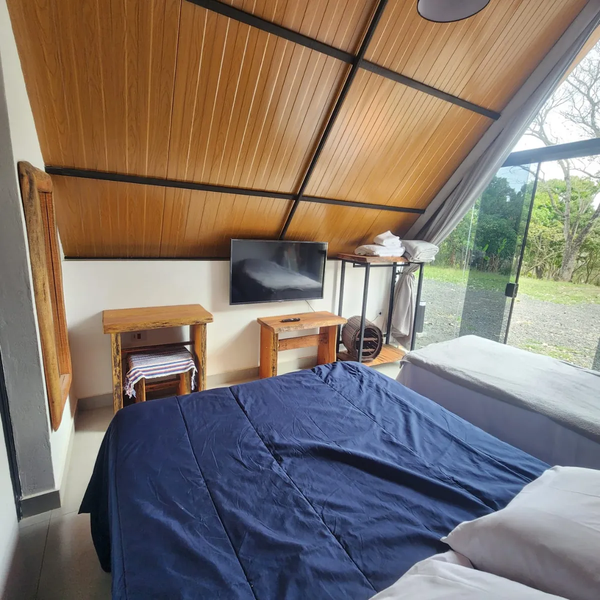 Quarto do chalezinho com parede de vidro e vista para o campo